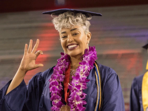 Photo of a student in Arizona Stadium as they smile and make the wildcat symbol with their hand