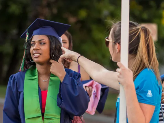 Image of a volunteer helping a student on Commencement Day