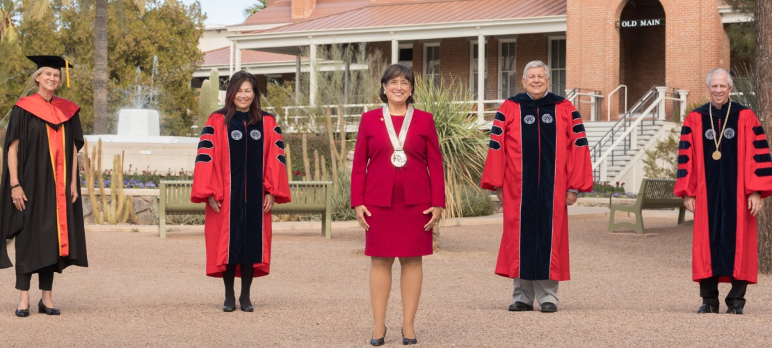 Dr. Brinton posing with university leadership in front of Old Main