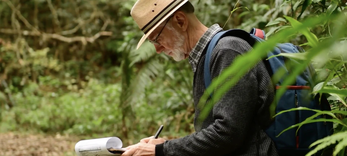 A second shot of Peter Chesson writing notes while conducting research in the jungle