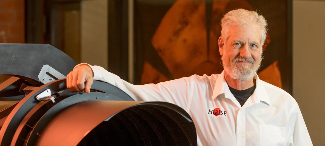 Alfred McEwen is seen posing next to a model of the HiRISE camera