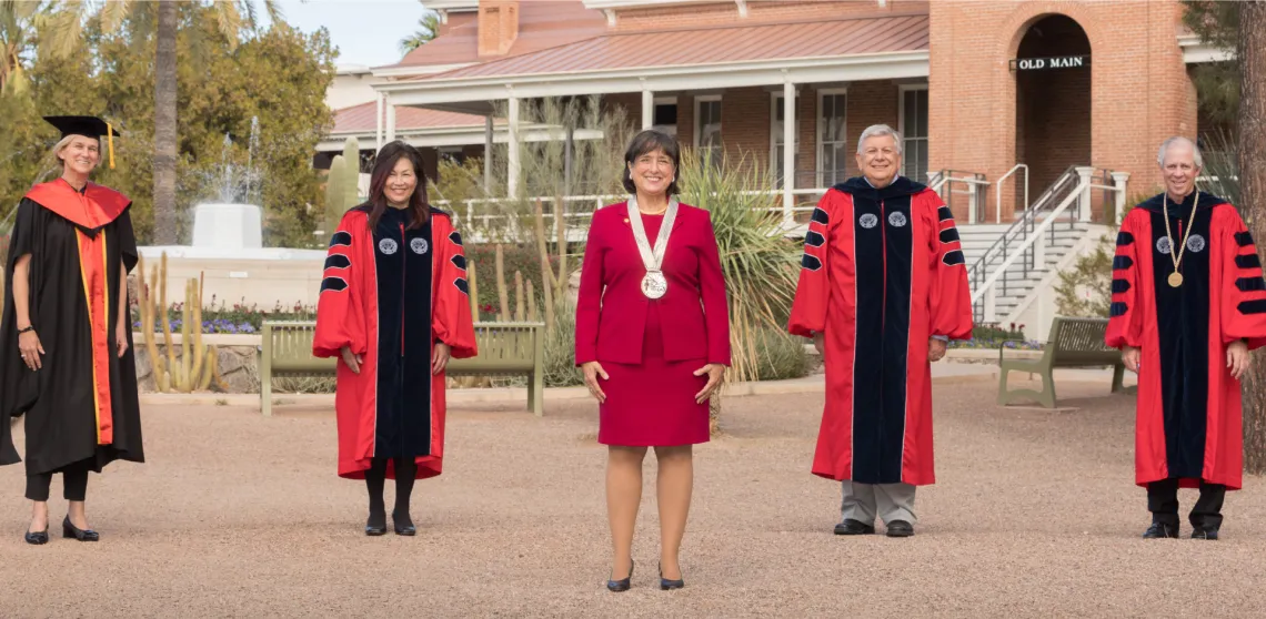 Dr. Brinton posing with university leadership in front of Old Main