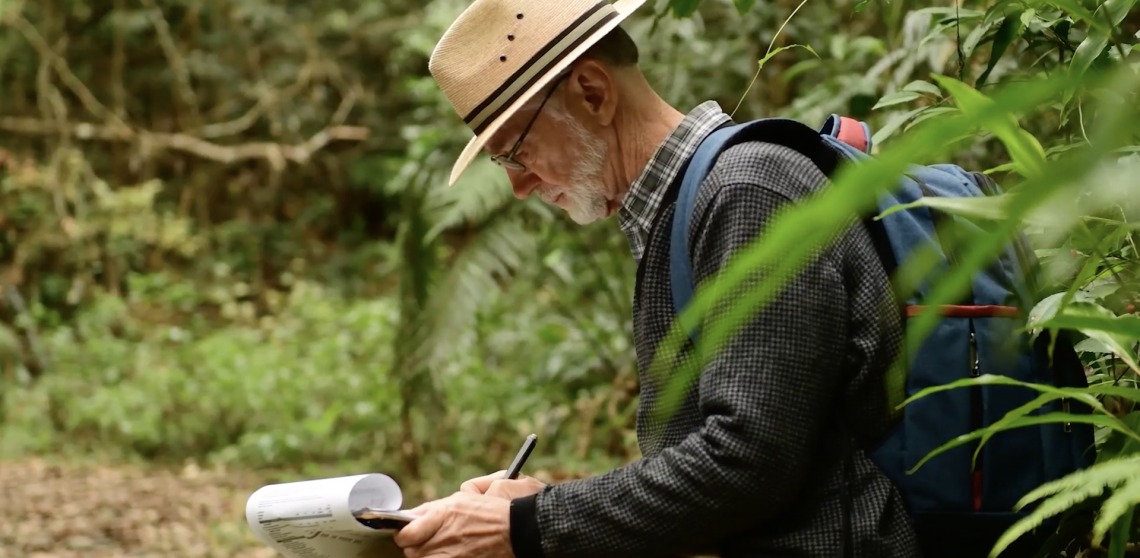 A second shot of Peter Chesson writing notes while conducting research in the jungle