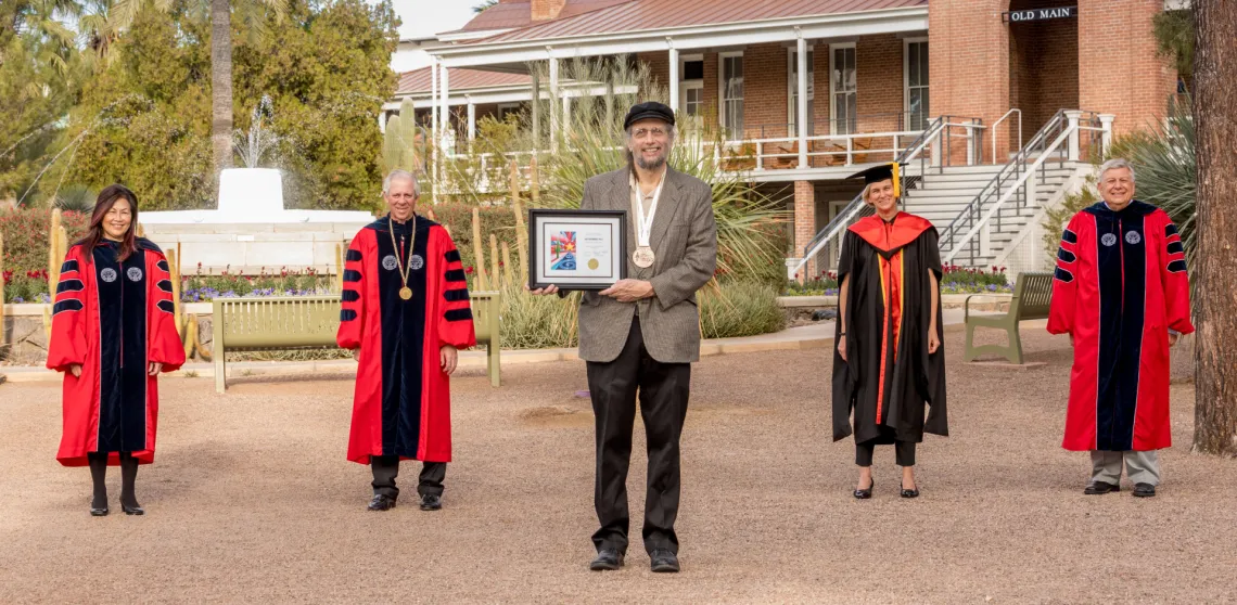 Jeff Greenberg is seen posing with university leadership in front of Old Main