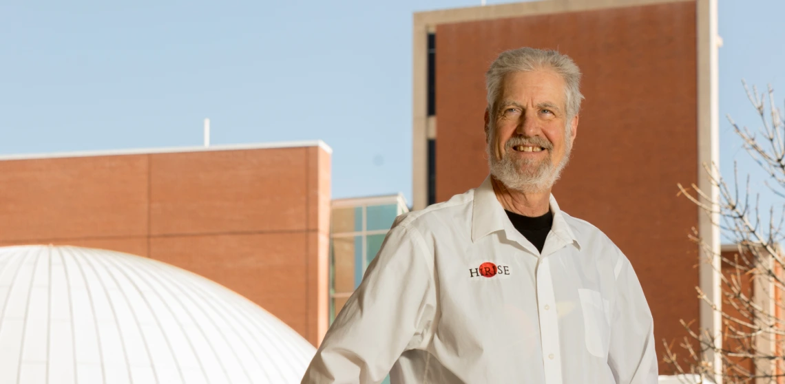 Alfred McEwen is seen smiling in front of the UArizona Planetarium